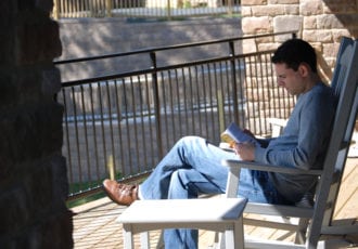 A man reading in a rocking chair.