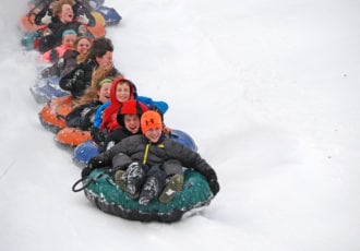 Kids tubing down a snow covered hill.
