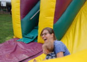 A woman taking her kid down a slide.