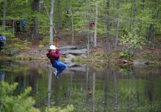 A person riding a zip line over water.