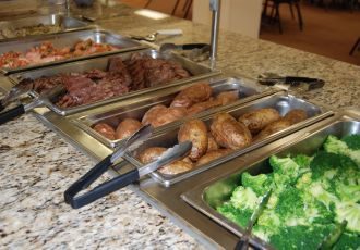 Steam trays with food in buffet line.